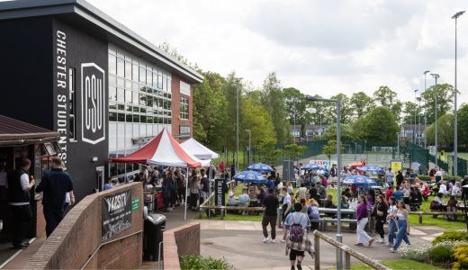 Crowd gathered outside Chester Students’ Union with stalls, tents, and seating areas in a lively outdoor event setting.