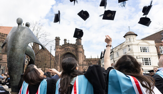 graduates throwing their caps in the air outside of cathedral