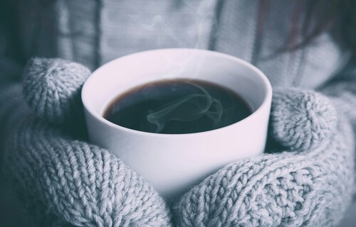 hands with mittens holding hot drink
