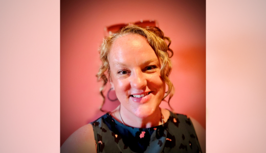 A person photographed against a pink backdrop in a formal portrait setting.