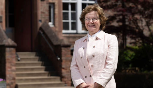 Vice-Chancellor, Professor Eunice Simmons standing outside a brick building near steps and landscaped grounds.