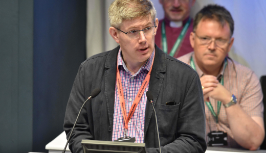 Speaker addressing an audience from a lectern during a conference.