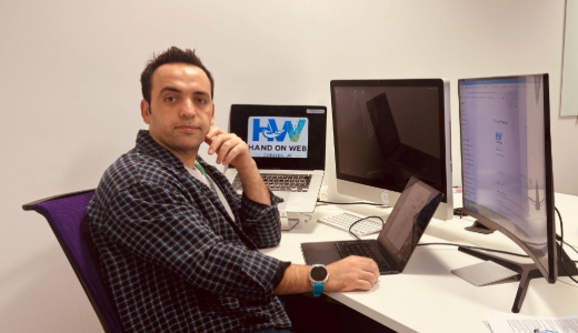 University alumnus working at a desk with multiple computer screens.