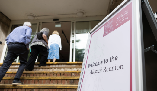 Welcome sign for the Alumni Reunion beside attendees entering the venue.