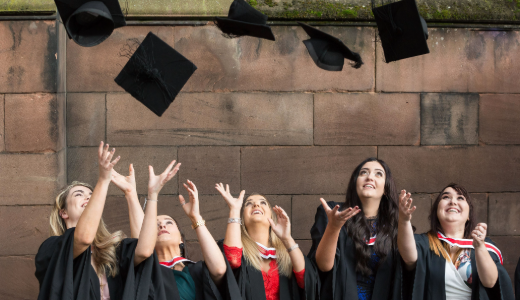 Graduates celebrating by throwing their mortarboards into the air.